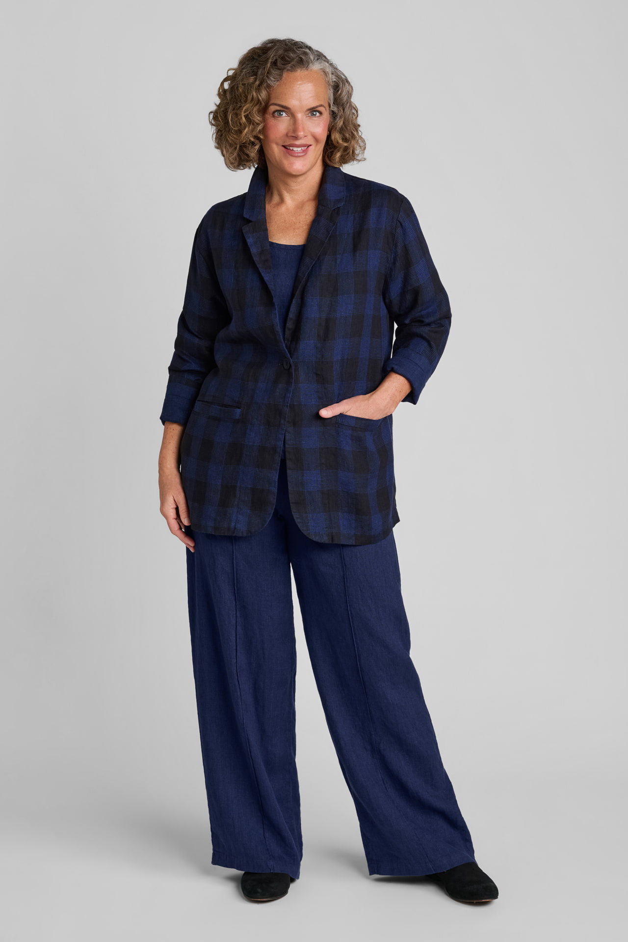 Woman in blue and black plaid blazer with blue linen pants